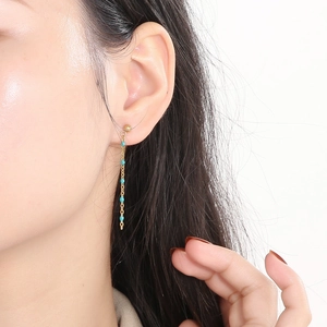 Bohemian gold chain tassel earrings with turquoise beads worn on a female model