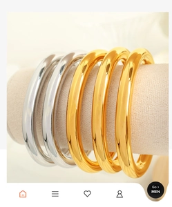 Polished gold and silver C-shaped wide bangles displayed on jewelry pedestals