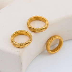 Three gold Tubogas snake rings set on minimalist stands with vintage industrial design