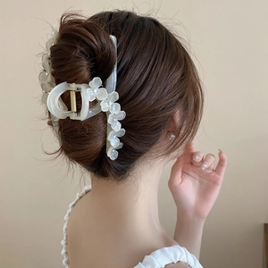 Détail d'une pince à cheveux fleur en résine crème avec strass sur des cheveux bruns