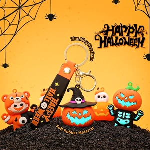 Luminous Halloween pumpkin and skull bear keychains with orange straps on a spooky background