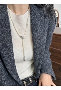 Detail of elegant Y-shaped pearl necklace with silver snake head and green gemstone eyes