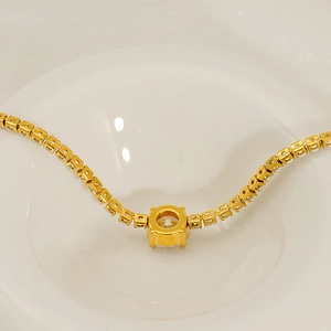 Detailed close-up of a gold-plated titanium steel bracelet featuring a round zircon pendant