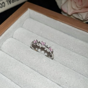 Macro detail of silver open ring with pink heart stones and star accents in jewelry box