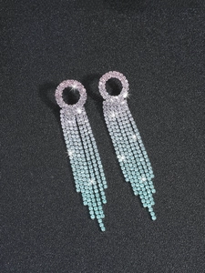 Close-up of long tassel earrings with purple to blue gradient rhinestones on black background