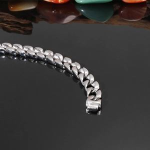 Gros plan d'un bracelet gourmette en acier inoxydable argenté avec fermoir sur noir