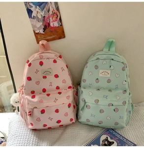 Close-up of strawberry and heart prints on pink and green nylon school backpacks