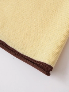 Détail du tissu en maille jaune clair avec bordure côtelée marron foncé contrastée