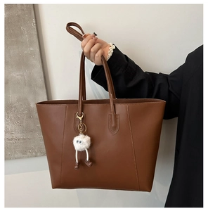 Vue détaillée d'un sac cabas marron classique avec un charmant pendentif en peluche blanc