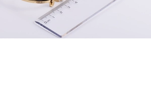Macro detail of a 18k gold-plated butterfly bracelet measured with a ruler for size