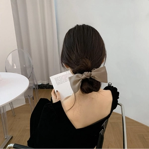 Beige oversized satin bow hair scrunchie shown on a bun hairstyle for a sweet elegant look