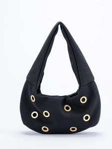 Detail of black suede shoulder bag featuring golden metal eyelets and rivet decorations