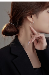 Detail view of s925 silver wave hoop earrings on model highlighting the twisted metal texture