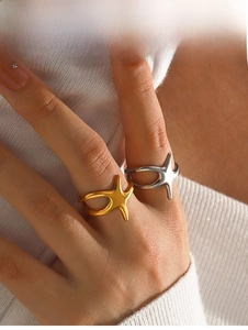 Detail view of irregular star-shaped rings in gold and silver finish on finger