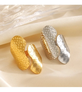 Detail of 18K gold and silver chunky textured rings on beige silk backdrop