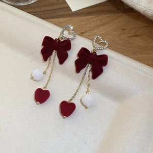 Detail of red velvet bow earrings with white fluffy pom-poms and rhinestone hearts