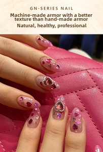 Detailed close-up of pink gradient press-on nails with heart gems and silver glitter