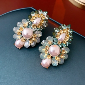 Gros plan de boucles d'oreilles fleuries avec perles roses et pétales en cristal