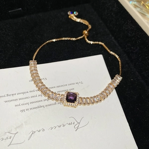 Détail d'un bracelet doré réglable avec un zircon violet carré et des cristaux brillants