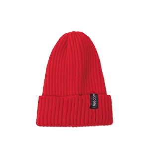 Detailed close-up of a red ribbed knit beanie featuring a black Freedom brand woven label