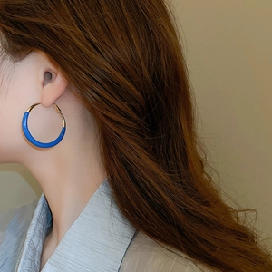 Close-up of geometric Klein blue and gold round hoop earring on model side profile