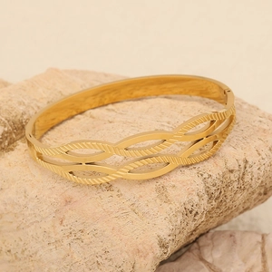 Brazalete abierto de acero inoxidable dorado con patrón de hojas sobre piedra natural