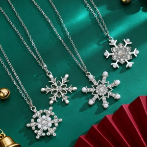 Close-up of four silver snowflake necklaces with rhinestones and pearls on green satin