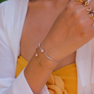 Close-up of 18K gold stainless steel bracelets and rings worn by a model in bright light