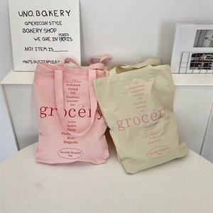 Détail de sacs de courses en toile rose et beige avec imprimé floral et lettrage chic