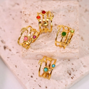 Golden moon and star rings with colorful natural stones set on beige textured stones