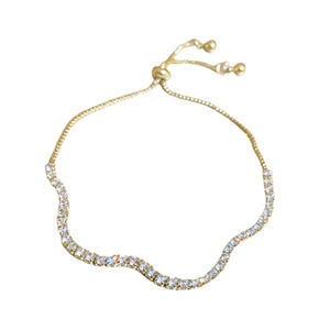 Adjustable wavy gold bracelet with white sparkling crystals on white background