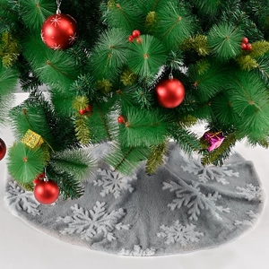 Detail of gray plush Christmas tree skirt with white snowflakes under a decorated tree