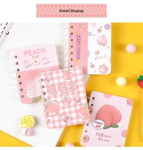Macro shot of peach theme spiral notebook with grid patterns and artistic pink covers