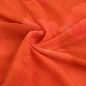 Gros plan du tissu en maille orange plissé montrant la texture fine et la transparence