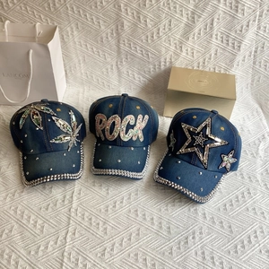 Close-up of three denim baseball caps featuring rhinestone leaf, star and rock patterns