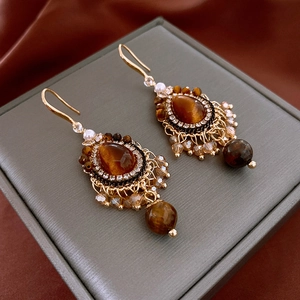 Détail de boucles d'oreilles vintage avec pierres marron et franges en perles