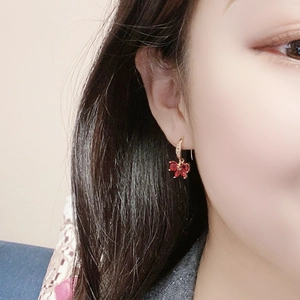 Close-up of red zircon flower earrings with gold hooks on a model, elegant jewelry detail
