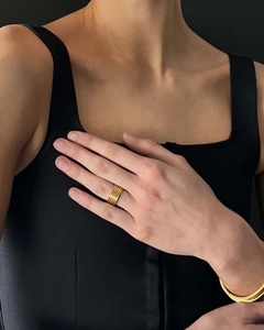Nahaufnahme eines eleganten 18K vergoldeten mehrlagigen Ring- und Armband-Sets an der Hand