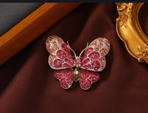 Macro shot of pink rhinestone butterfly brooch on dark vintage silk background