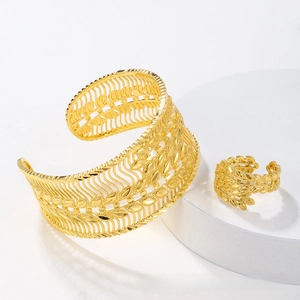 Detailed view of hollow leaf pattern on golden cuff bracelet and matching open ring set