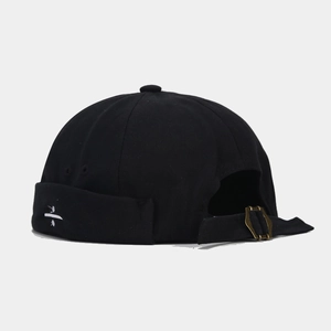 Close-up of canvas miki hat featuring white cross embroidery and vintage metal buckle