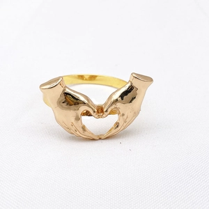 Detail shot of a gold heart-shaped hands gesture napkin ring on white fabric