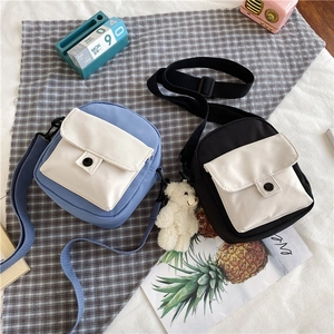 Vue à plat de sacs à bandoulière en toile bleu et noir avec breloque ours mignon