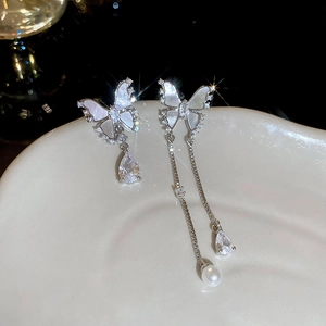 Macro view of asymmetric butterfly earrings with mother-of-pearl, zircons and a pearl drop