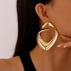Close-up of chunky gold irregular geometric hoop earrings worn by a model in profile