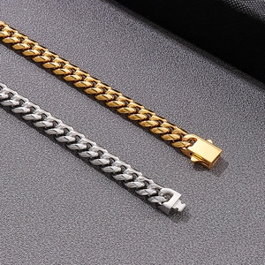 Close-up of gold and silver Cuban link chains with square clasp on grey background