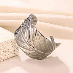 Detailed macro view of silver feather pattern texture on stainless steel wide cuff bracelet