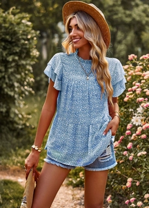Detailed view of floral blue top with ruffle sleeves and mock neck on model