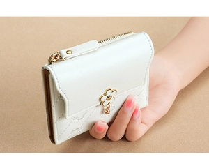 Close-up of model holding white quilted short wallet with floral buckle and gold zipper