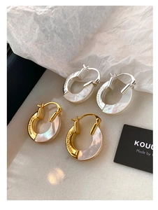 Close-up of gold and silver hoop earrings featuring mother of pearl and Confession engraving